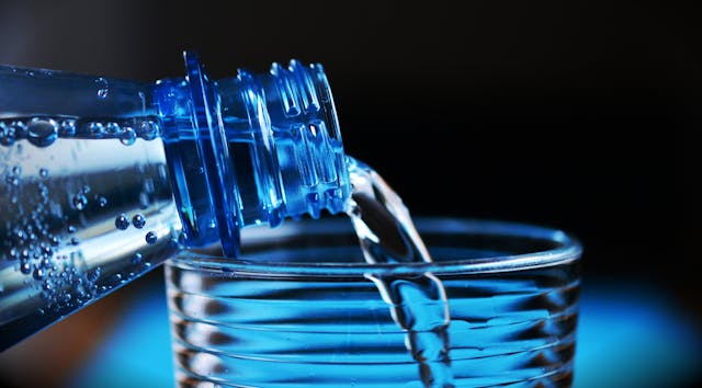 Close-up of water pouring out of the water bottle into a glass